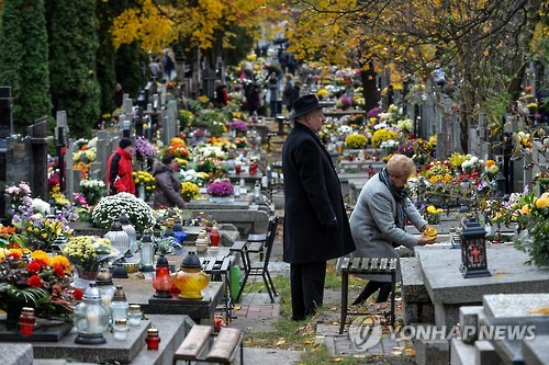 서양에서 기독교의 모든 성인을 기념하는 축일인 만성절(萬聖節 All Saints' Day)을 맞아 2016년 11월 1일 폴란드 수도 바르샤바 인근 볼라 공원묘지에서 참배객이 헌화하는 모습. [EPA=연합뉴스 자료사진]