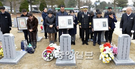 순직자 유족 등이 고인의 묘역에서 훈장을 내보이며 묵념하고 있다. 대전=프리랜서 김성태