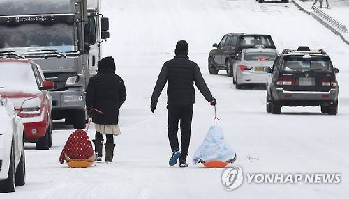(제주=연합뉴스) 박지호 기자 = 폭설이 내린 10일 오전 담요를 뒤집어 쓴 어린이들이 제주시 아라동 주택가 도로에서 썰매를 타고 있다. 2017.2.10      jihopark@yna.co.kr