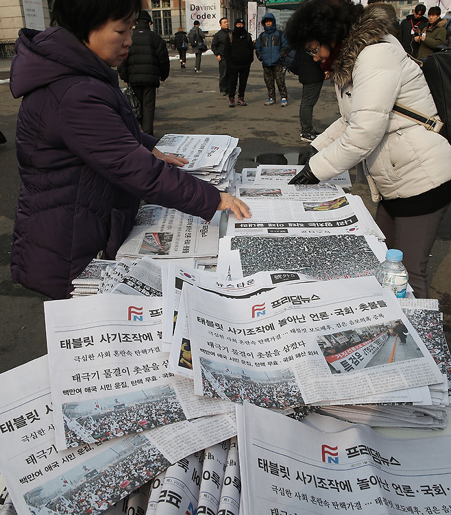 탄기국 회원들이 설 연휴를 하루 앞둔 1월26일 서울역 광장에서 귀성객을 상대로 탄핵 반대 입장을 알리려고 자체 제작한 신문을 배포하고 있다. ⓒ 연합뉴스