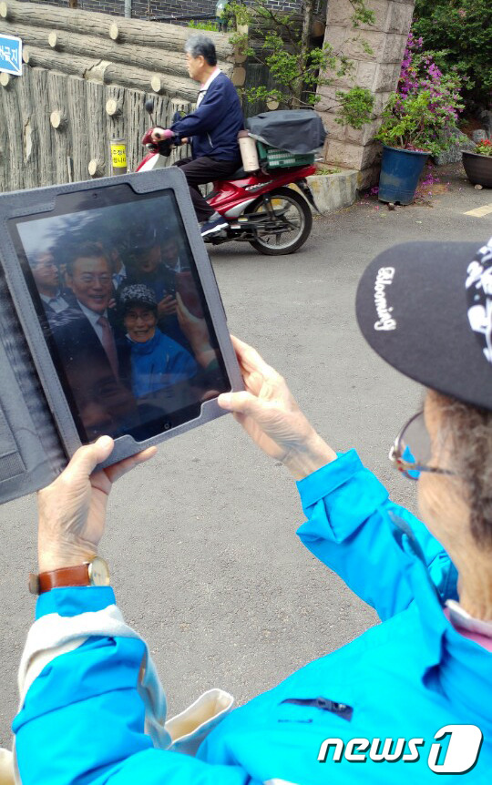 11일 오전 서울 서대문구 문재인 대통령 자택 앞에서 대통령과 함께 사진을 찍은 김중길씨(83·여)가 자신이 찍은 사진을 보며 기뻐하고 있다. © News1