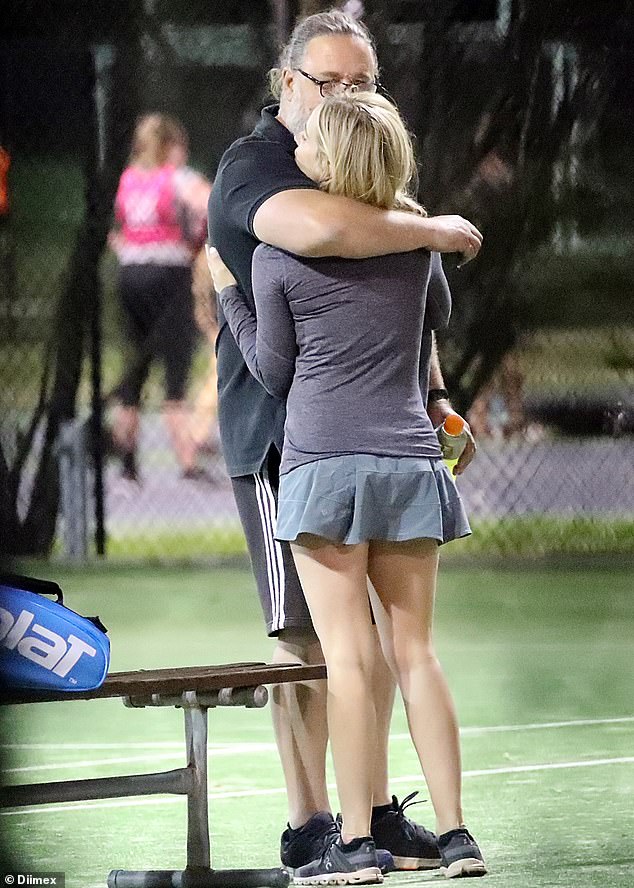 Russell Crowe, 56, finds comfort in the arms of his friend Britney Theriot, 30, as the pair cuddle up to one another on a tennis court in Sydney