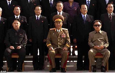 First image: North Korean leader Kim Jong-il (middle, in front row) and his third son and heir Jong-un (left, also in front row) pose with attendees of the communist country's ruling Workers' Party at Kumsusan Palace