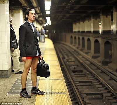 Waiting for a train: A man wearing a suit jacket and holding a bag stands on the platform at a New York Subway station