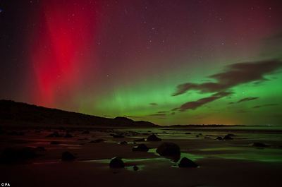 Breathtaking: A streak of red can be seen in the sky as dozens of rocks rest on Embleton Bay in Northumberland below