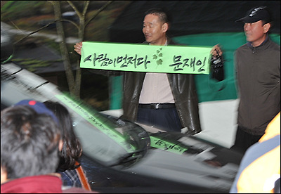  충북 음성 수정산농원에 문재인 후보가 탄 승합차가 도착하자 지지자로 보이는 사람이 '사람이 먼저다'란 펼침막을 들어 보이고 있다.