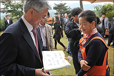  충북 음성 수정한 농원을 방문한 문재인 후보가 농원주인 남궁영자씨에게 '사람이 먼저입니다'라고 쓴 서명지를 건네고 있다.