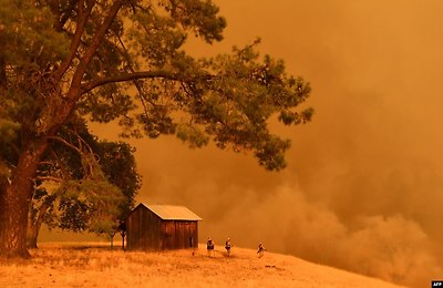 미국 캘리포니아 귄다의 언덕에서 소방관들이 화재로 솟아오르는 연기를 보고 있다.