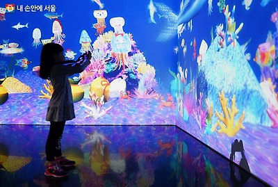 팀랩월드에서 본인이 그린 그림을 찾아 사진 찍는 어린이