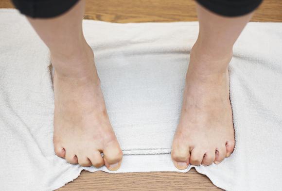 수건을 깔고 발가락을 구부리고 있는 발