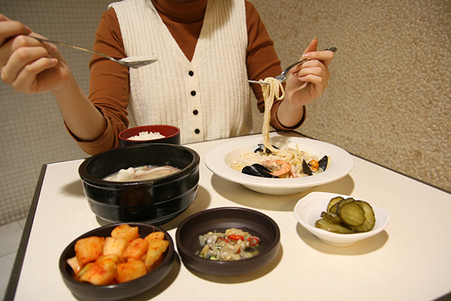 한 사람이 한 손에는 스파게티를, 한 손에는 국밥을 들고 있다