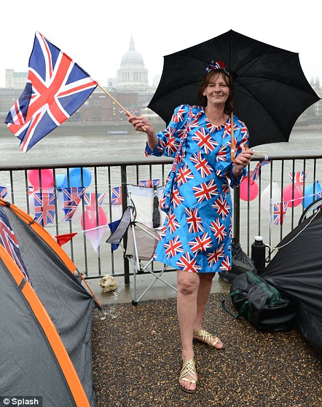 A woman wearing a Union flag dress waits on the river bank for the procession to start