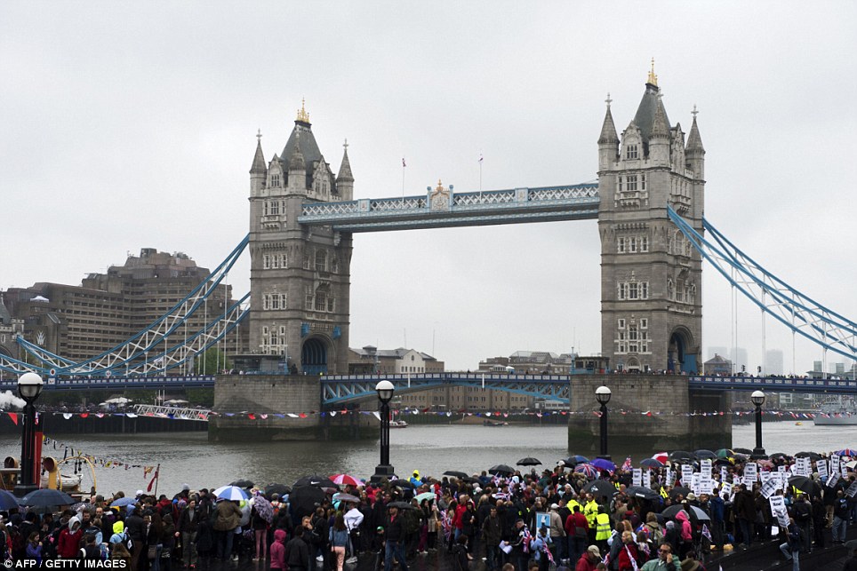 Crowds of people gather near Tower Bridge to see the Queen as she cruises along on the Thames