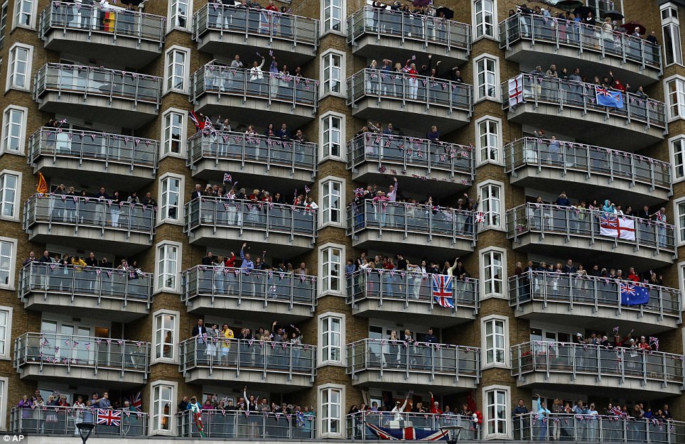 Rooms with a view: People wave from a building on the river bank as a flotilla of 1,000 vessels passes by during the Thames River Pageant