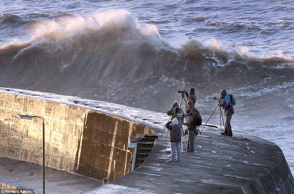 Enthusiastic photographers are on the cobb wall at Lyme Regis in Dorset for the biggest high-tide for many years this morning