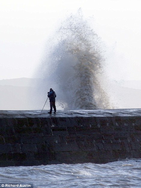 A photographer stands on the Cobb wall at Lyme Regis in Dorset