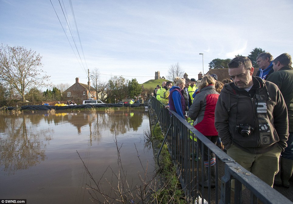 Looking: Residents of Burrowbridge watch as the hide tide starts to breach the banks of the River Parrett. Flood water continues to rise on the Somerset Levels
