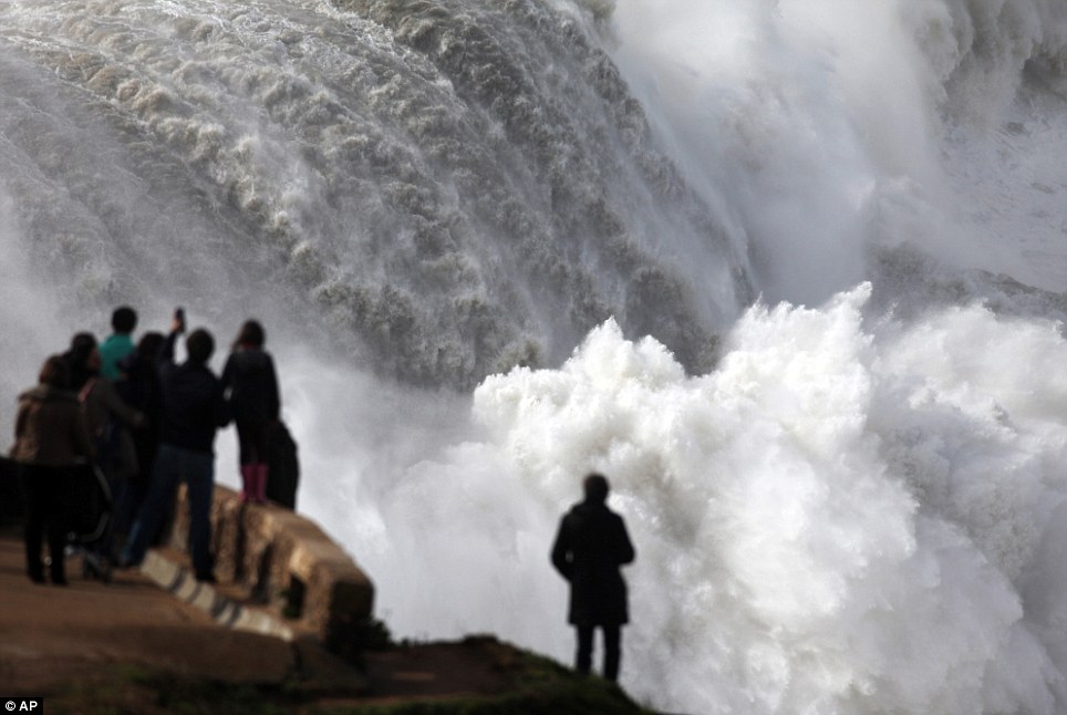 Passers-by watch huge waves breaking at the Praia do Norte, or North beach, outside the fishing village of Nazare, in the central coast of Portugal