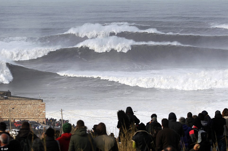 Epic: A crowd watches huge waves approaching at the Praia do Norte outside the fishing village of Nazare, in Portugal