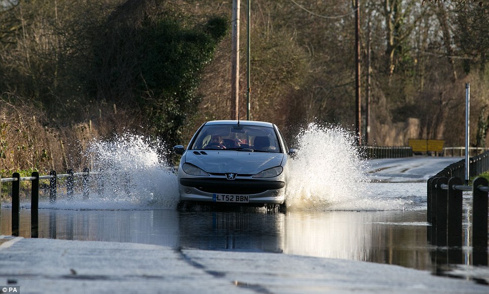 Motoring on: A car drives through a flooded road next to the River Thames in Chertsey, Surrey
