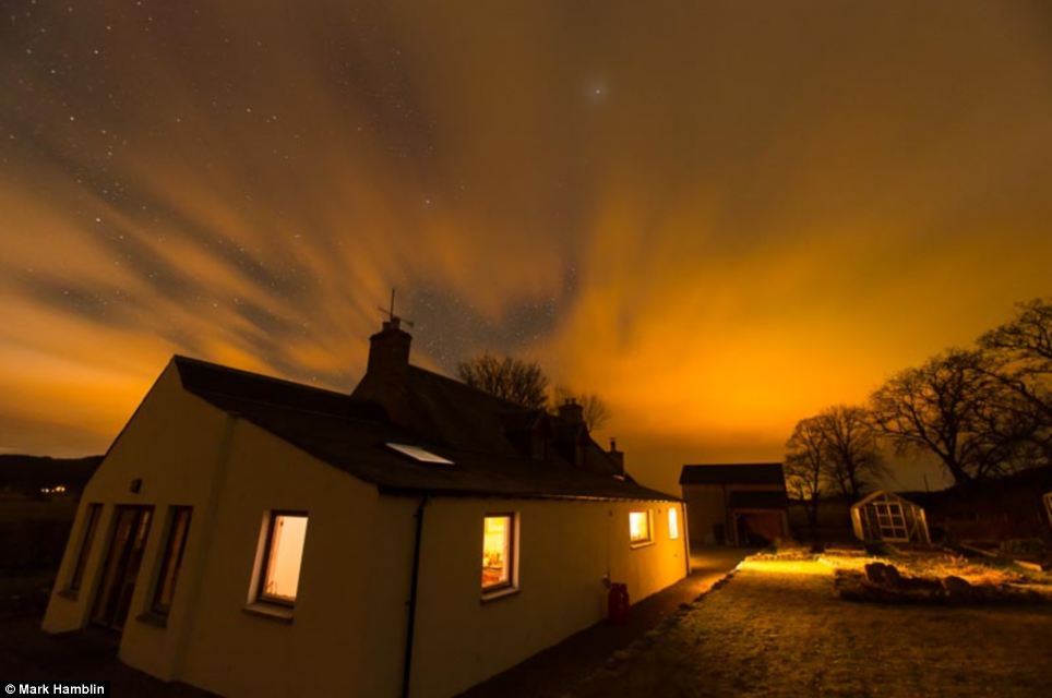 Mesmerising: A beautiful display of lights is pictured above the house in Carrbridge - giving the property warm yellow glow