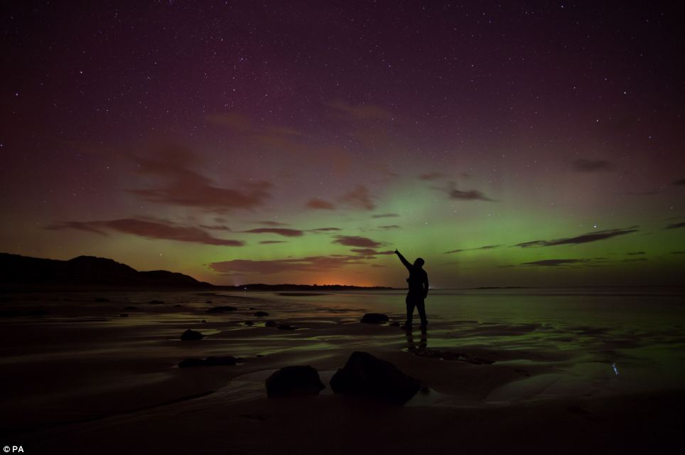 Amazing: A sightseer points at the Northern Lights at Embleton Bay in Northumberland