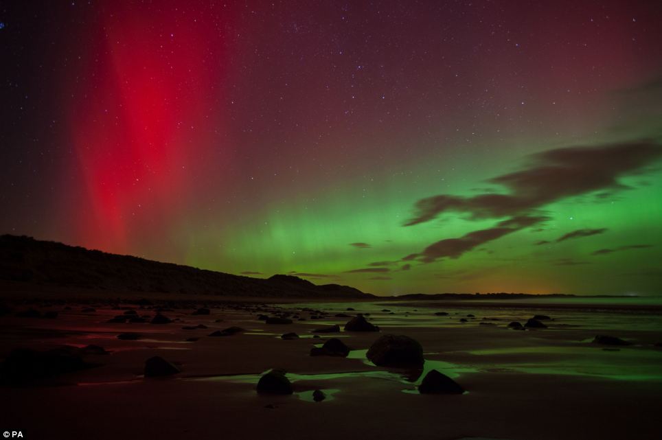 Breathtaking: A streak of red can be seen in the sky as dozens of rocks rest on Embleton Bay in Northumberland below