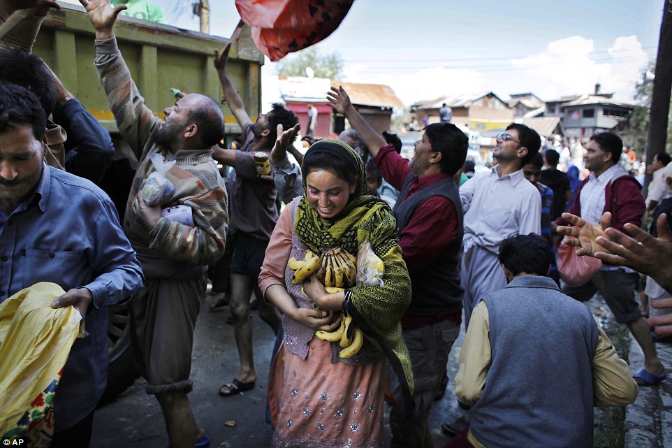 Relief: One flood victim clutched a bunch of bananas as volunteers distributes aid in Srinagar. The floods have washed away crops and roads, leaving supplies scarce