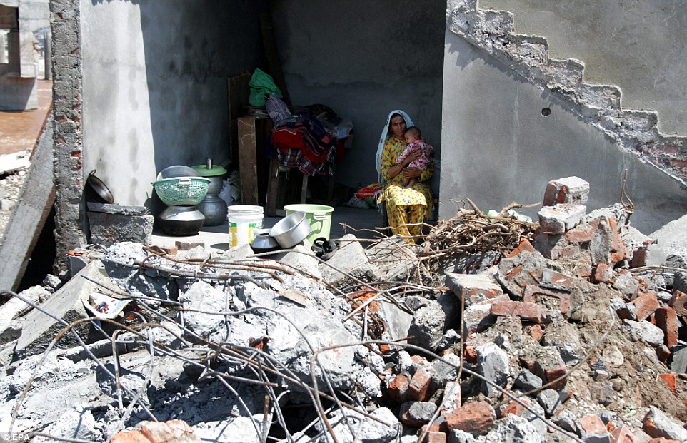 An Indian flood affected mother with her child sits inside her damaged house today in flood-hit Jammu, the winter capital of Indian Kashmir