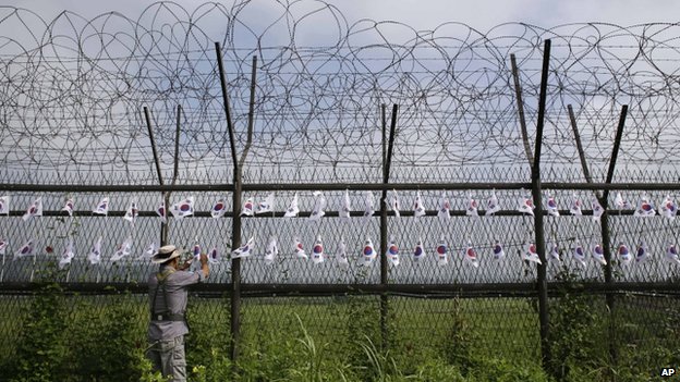 A South Korean man adjusts the national flags on the military wire fence at the Imjingak Pavilion near the border village of Panmunjom, which has separated the two Koreas since the Korean War, in Paju, north of Seoul, South Korea, 24 August 2013