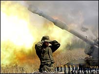 Israeli soldier covering ears near firing tank