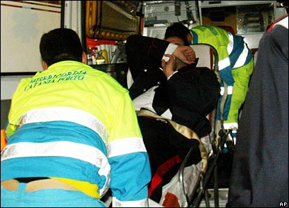 An injured policeman, on a stretcher,  is carried out of an ambulance at Catania's Garibaldi hospital