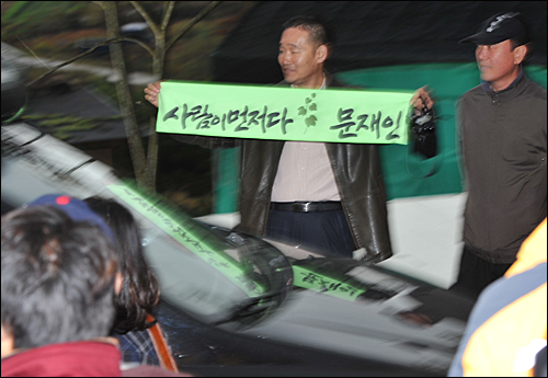 충북 음성 수정산농원에 문재인 후보가 탄 승합차가 도착하자 지지자로 보이는 사람이 '사람이 먼저다'란 펼침막을 들어 보이고 있다.