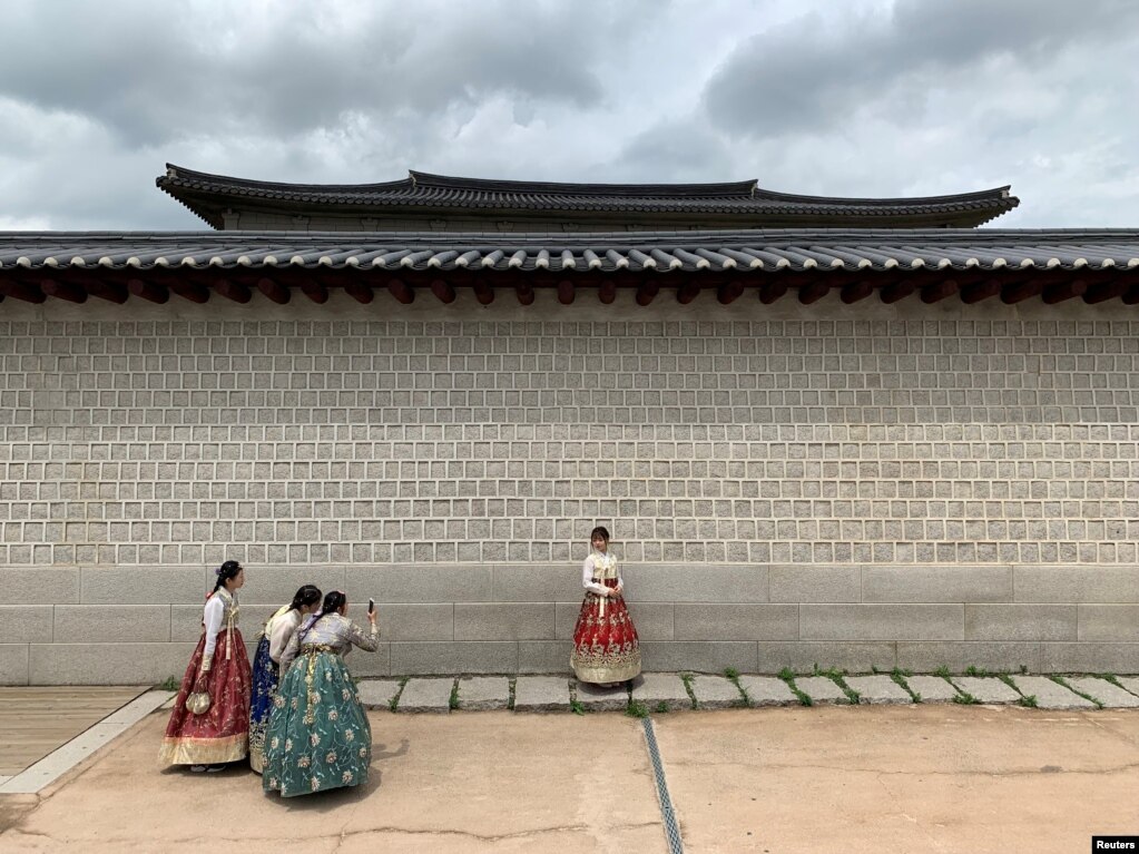 한국 서울 경복궁 앞에서 한국 전통 의상인 한복을 입은 관광객들이 사진을 찍고 있다.