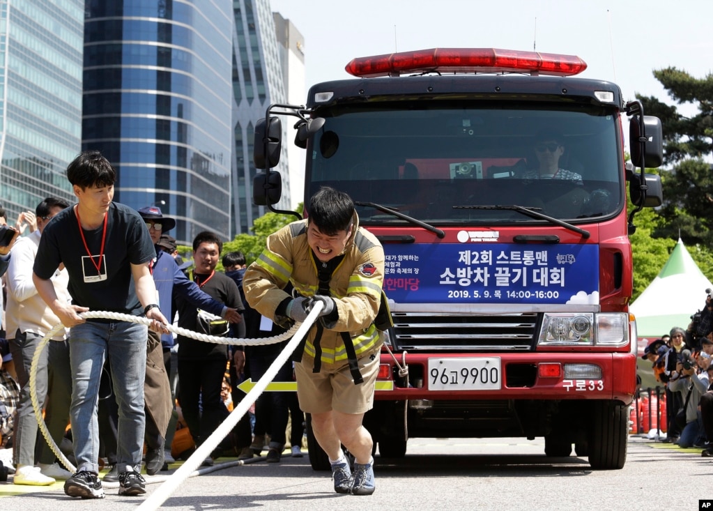 한국 서울에서 열린 '서울 안전한 마당'에서 소방관이 줄을 사용하여 소방차를 끌고 있다.