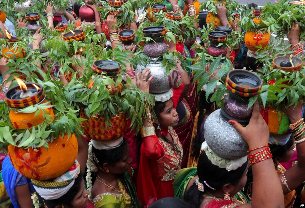 인도 하이데라바드에서 힌두교 축제인 '보나루(Bonalu)'가 열린 가운데  여성 신자들이 강황과 인도멀구슬나무 잎으로 장식된 화분을 머리에 이고 이동하고 있다.