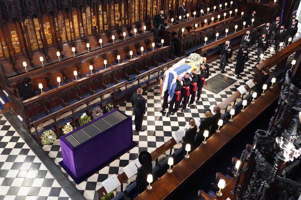 Queen Elizabeth II (L) watches as pallbearers carry the coffin of Britain's Prince Philip, Duke of Edinburgh during his funeral inside St George's Chapel in Windsor Castle in Windsor, west of London, data-on April 17, 2021.