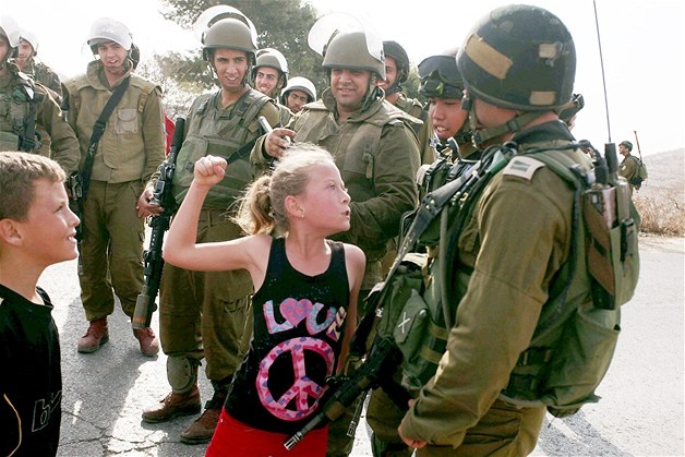 A Palestinian girl in a shirt decorated with the word 'love' & a peace sign faces off with Israeli soldiers during a Nov. 4 protest against the expansion of the nearby Jewish settlement of Halamish, in the West Bank village of Nabi Saleh.: