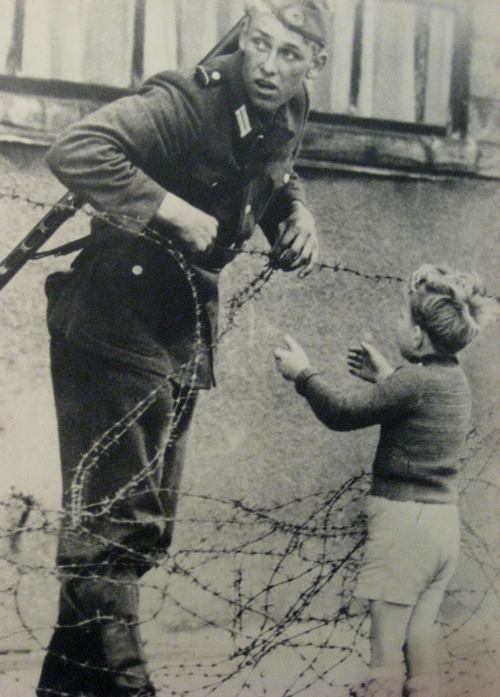 an-east-german-soldier-helps-a-young-boy-cross-the-barbed-wire-which-was-a-marker-for-where-the-berlin-wall-would-soon-be-built-the-guard-was-caught-and-immediately-punished-on-august-1.jpg
