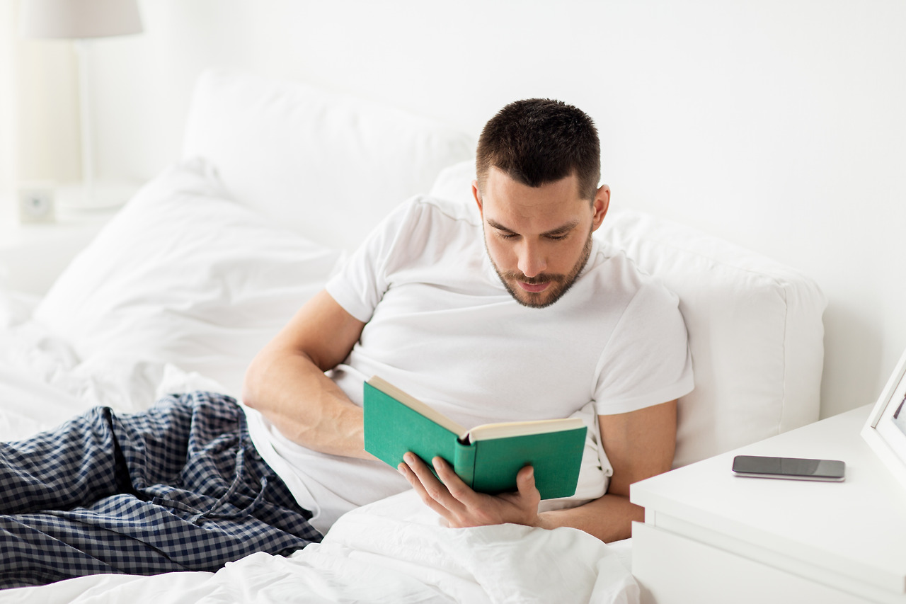 man-reading-book-in-bed-at-home-PC73E43.jpg