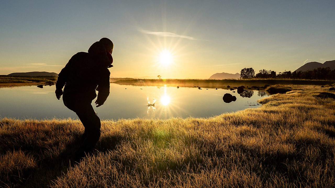 man-throwing-a-stone-into-a-calm-lake-during-beautiful-sunrise-2210x1243.jpg