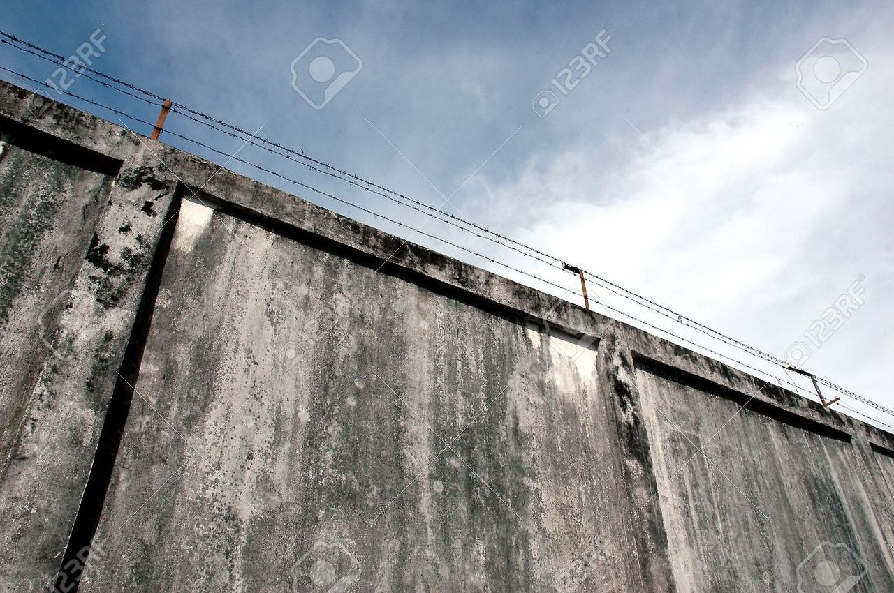 11817865-the-prison-walls-with-high-walls-and-barbed-iron-wire-Stock-Photo.jpg