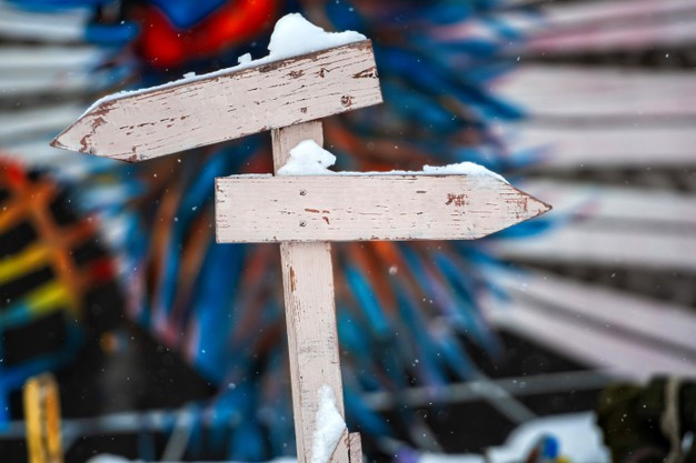 snowy-wooden-signpost-with-two-nlank-arrows-colorful-blurry-surface_132273-1916.jpg