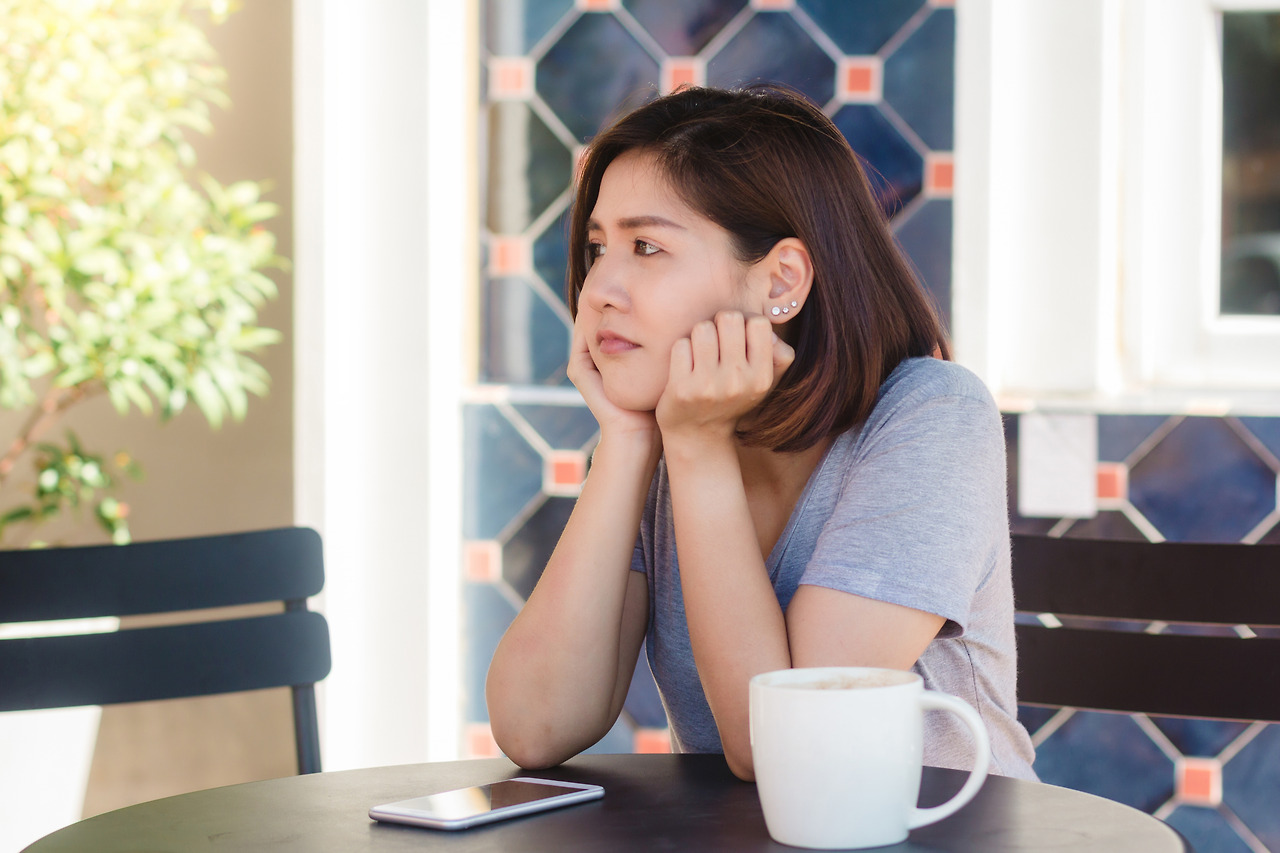 cheerful-asian-young-woman-sitting-cafe-drinking-coffee-using-smartphone-talking.jpg