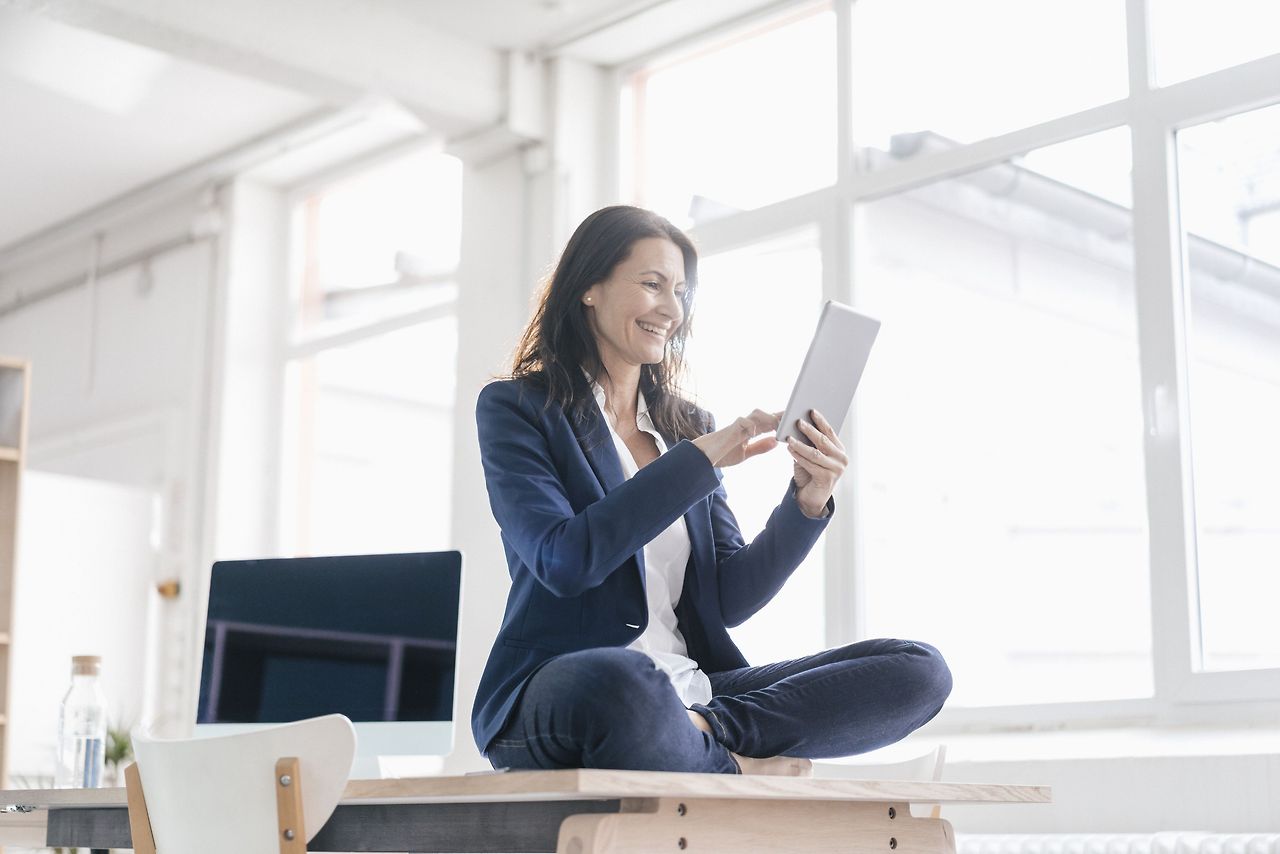 businesswoman-sitting-on-desk-in-a-loft-using-tablet-748328415-5afb4139a9d4f900369b44be.jpg