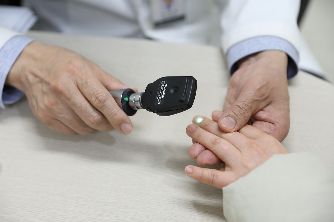 [사진] 일산백병원 소아청소년과 김영대 교수가 진료 중 아이 손끝을 살펴보고 있다..jpg