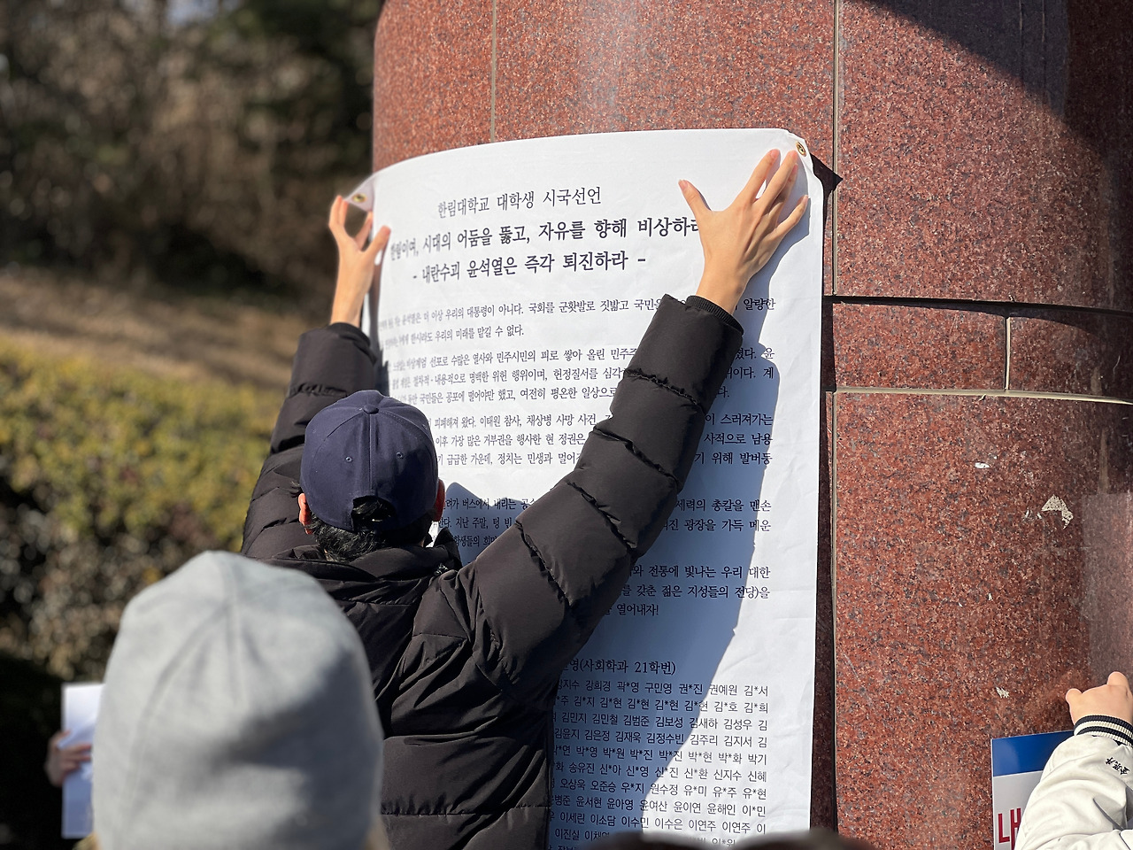 한림대학교 정문 앞에 시국선언문을 부착하고 있다(직접 촬영).jpg