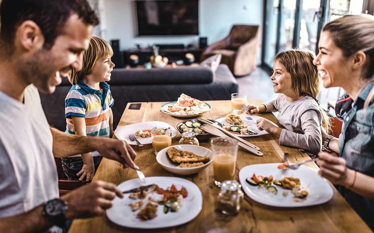 young-happy-family-talking-while-having-lunch-GettyImages-1132278686.jpg