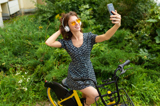 young-caucasian-woman-with-perfect-smile-plump-lips-glasses-earphones-walks-in-nature-ride-a-bike-and-records-a-video-do-selfie_88135-15414.jpg
