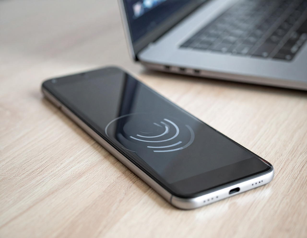 Firefly A cell phone is vibrating on the desk where a laptop is placed. 171495.jpg